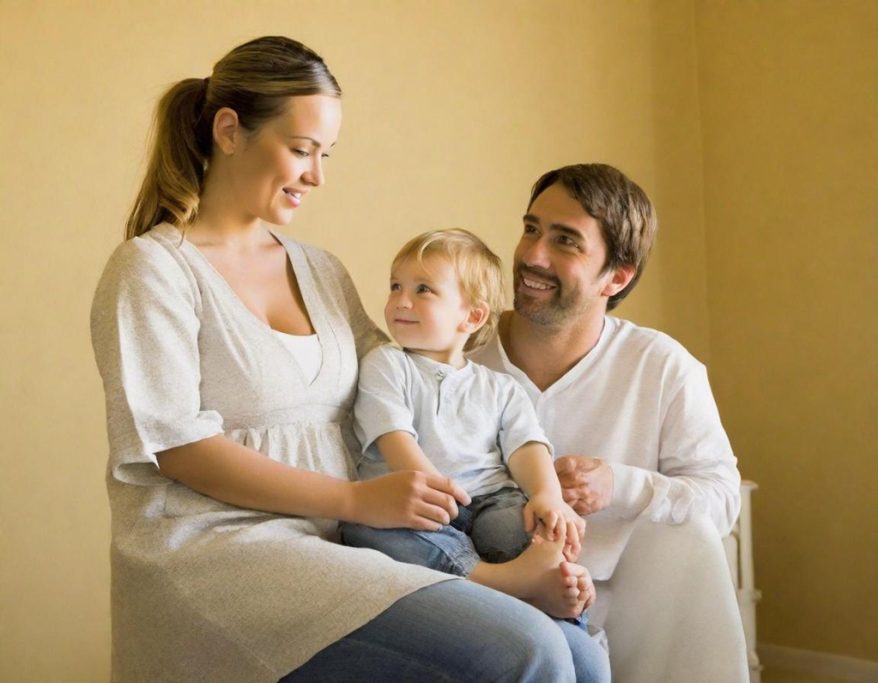 Familie sitzt zusammen in einem hellen Raum, glücklich und lächelnd.